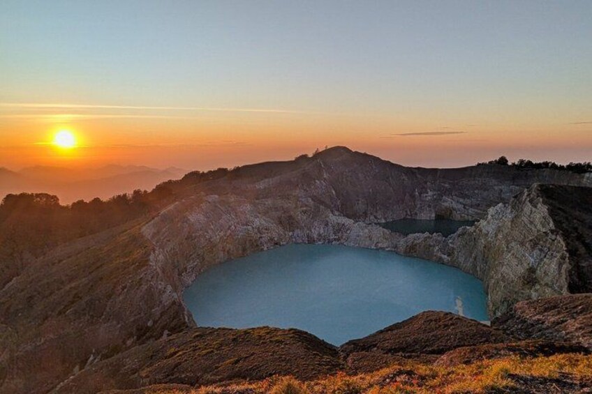 A sunrise over a crater lake surrounded by rocky terrain. 1