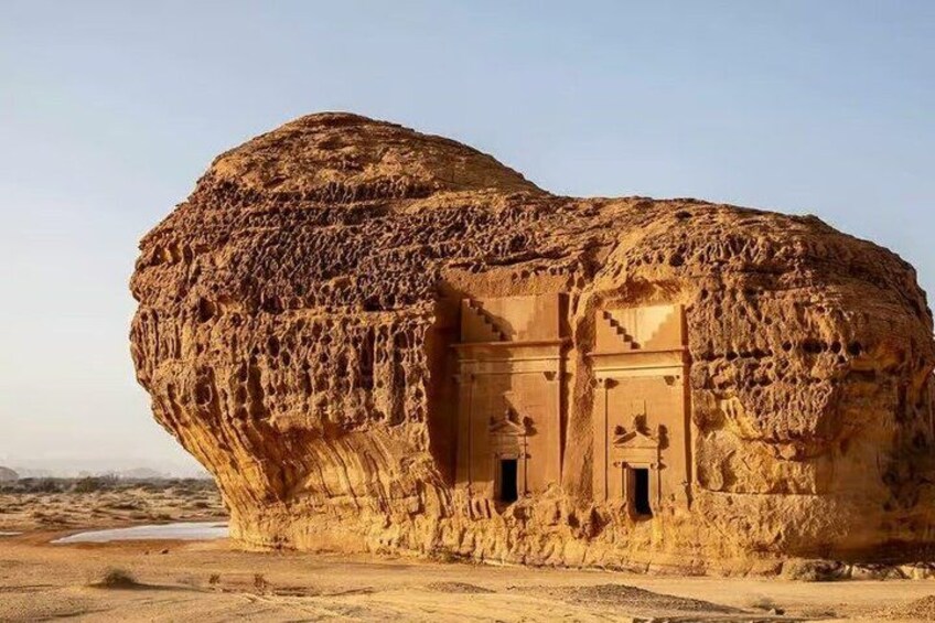 A large rock formation with carved doorways and a flat-topped structure. 3