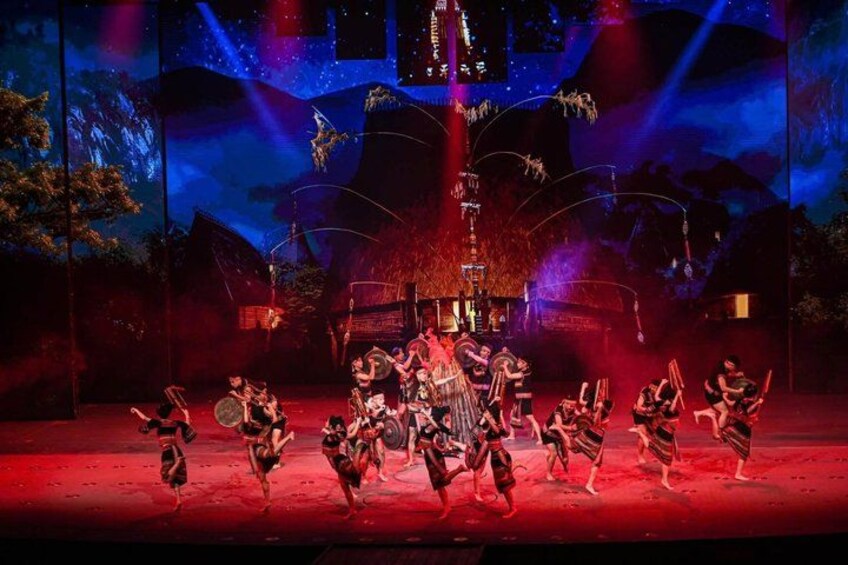 A stage performance with dancers in traditional costumes, a central figure, and a backdrop with a mountain and starry sky. 2