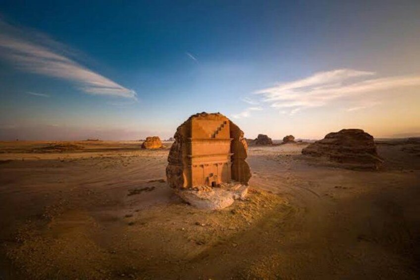 A desert landscape with a prominent rock formation resembling a stepped pyramid. 1