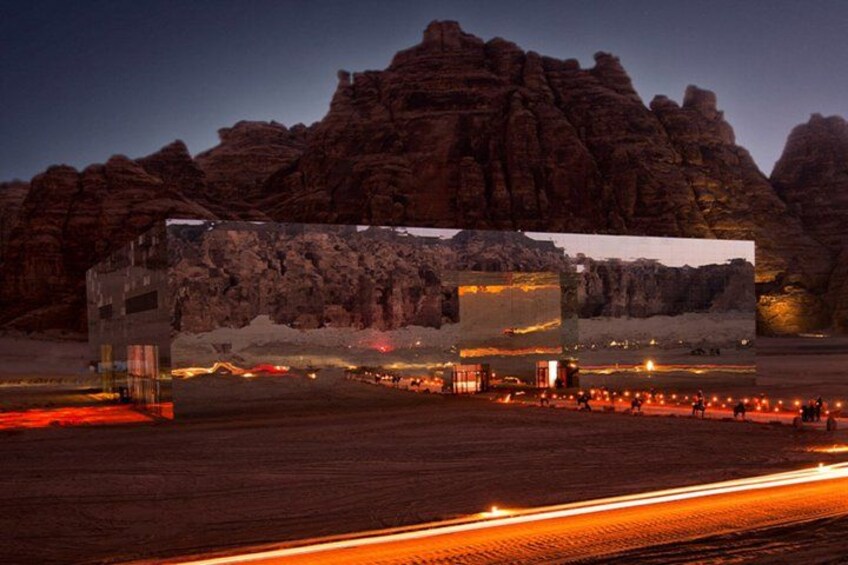 A desert landscape with a large building featuring a reflective surface. 3