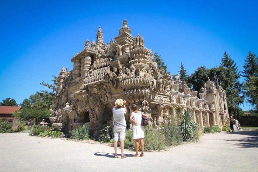 A large, intricately carved temple structure with visitors standing in front. 3
