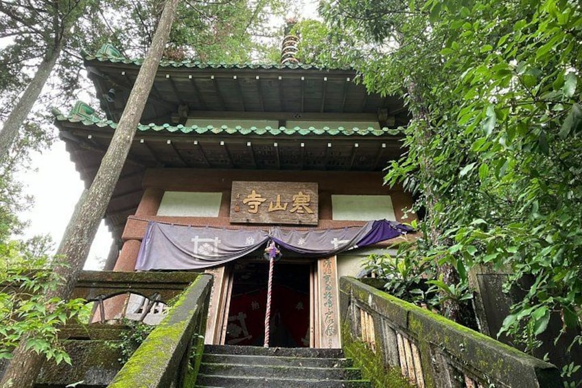A traditional Japanese temple entrance with a staircase leading up to a covered walkway. 3