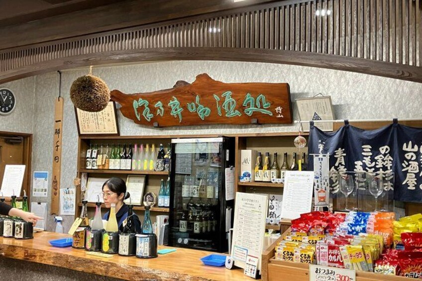 A store with a wooden sign, shelves with bottles, and a counter with various items. 3