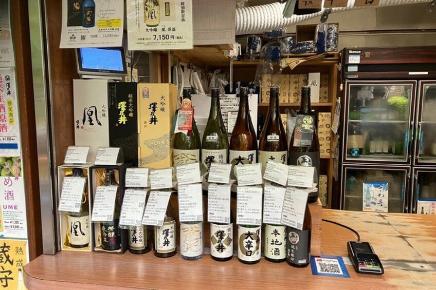A variety of sake bottles and boxes on display with price tags. 5