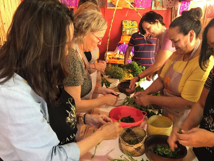 A group of people preparing food, with vegetables and bowls on the table. 1