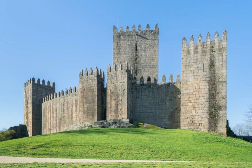 A large stone castle with multiple towers and a grassy hill in the foreground. 4