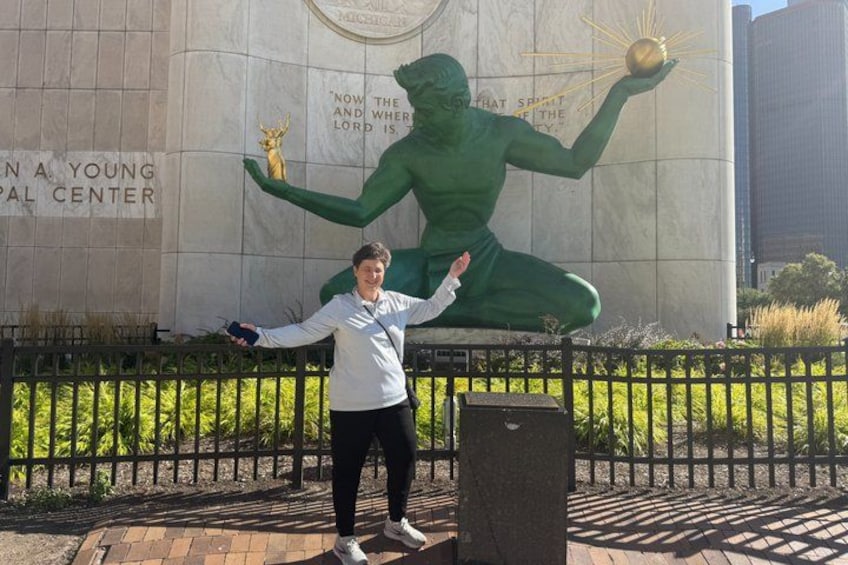 A person standing in front of a large green statue with a golden sphere. 4