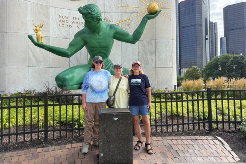 A statue of a muscular figure holding a golden ball, with a plaque in the background and a cityscape in the distance. 5