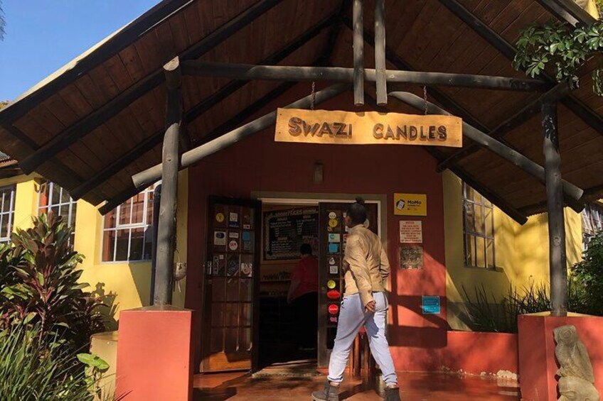 A building with a sign reading 'Swazi Candles' and a person standing at the entrance. 2