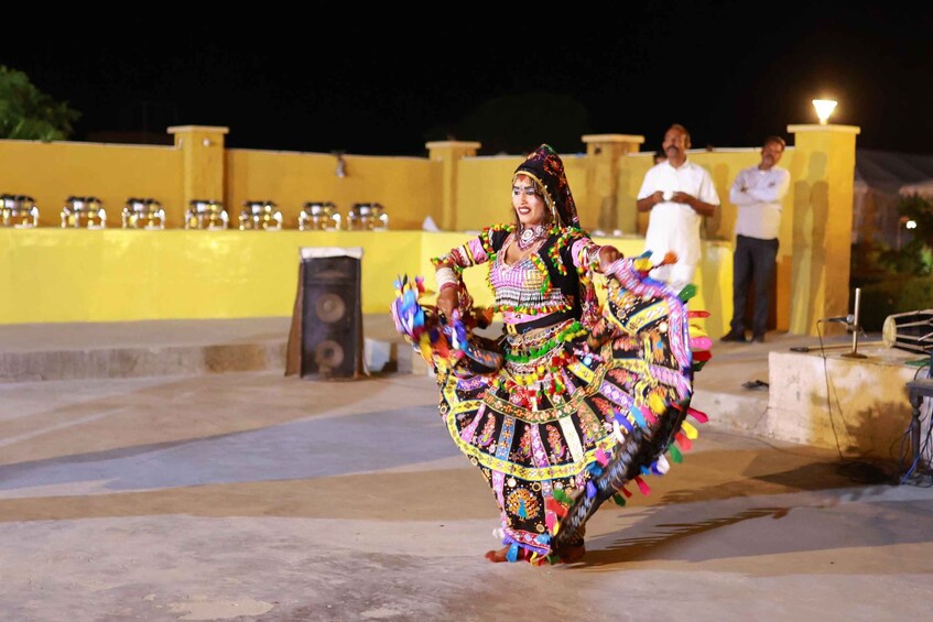 Una persona vestida con un traje tradicional colorido bailando. 1