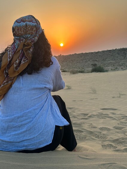 Una persona sentada sobre dunas de arena durante el atardecer. 2