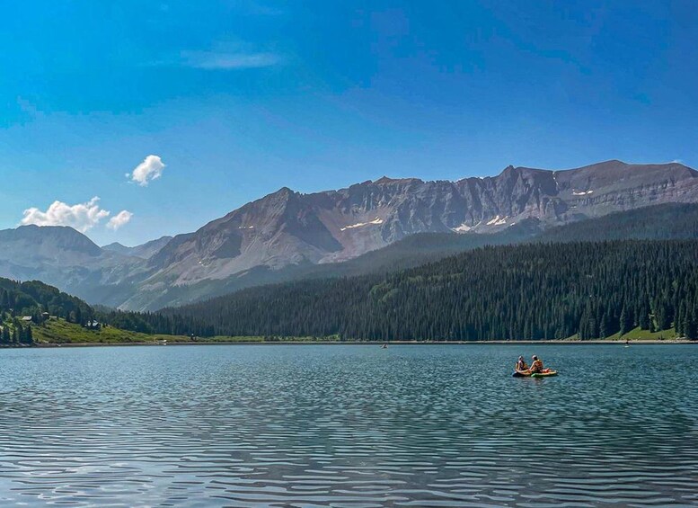 A calm lake with mountains in the background and two people kayaking. 3