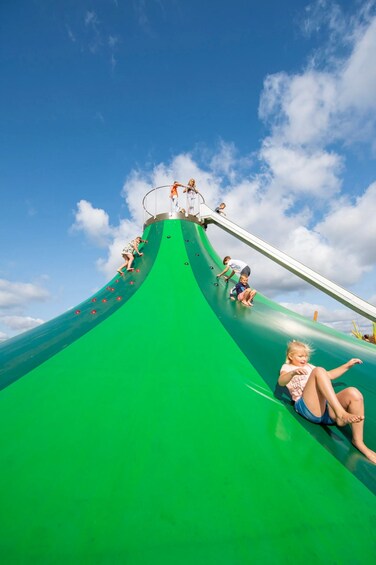 A green water slide with children climbing up and sliding down. 4