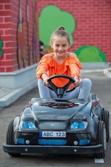 A child driving a toy car with a license plate ABC 123. 2