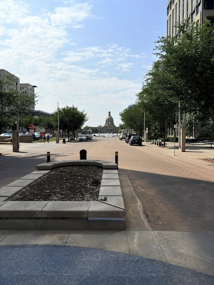 A city street with a fountain, trees, and a large building with a dome in the distance. 5