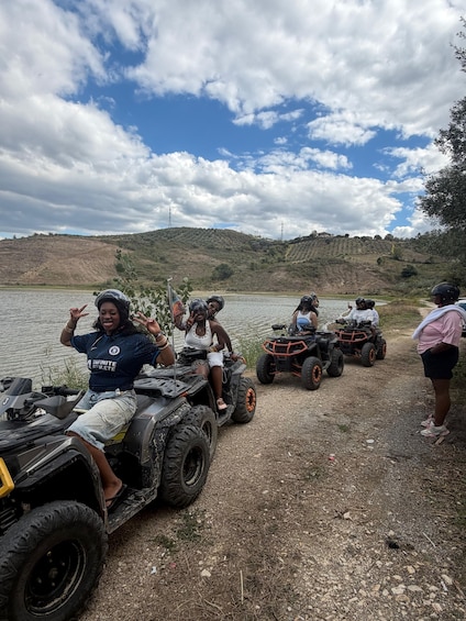 People on ATVs near a body of water with hills in the background. 4