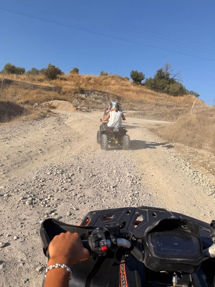 A dirt road with a person riding an ATV in the distance. 5