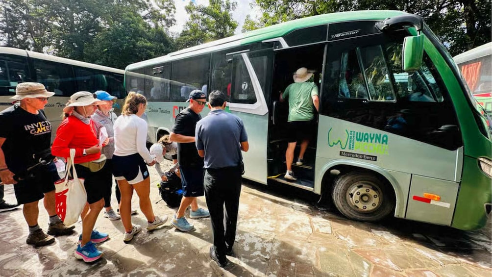 Un groupe de personnes monte à bord d’un autobus vert et blanc sur lequel on peut lire les mots « Wayna Pichu ». 5