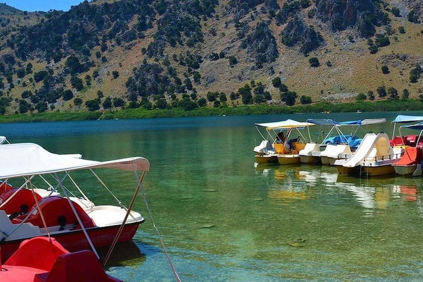 A lake with boats docked along the shore, surrounded by hills. 3