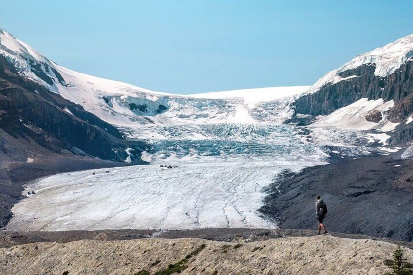 A glacier with a person standing on a rocky outcrop. 2