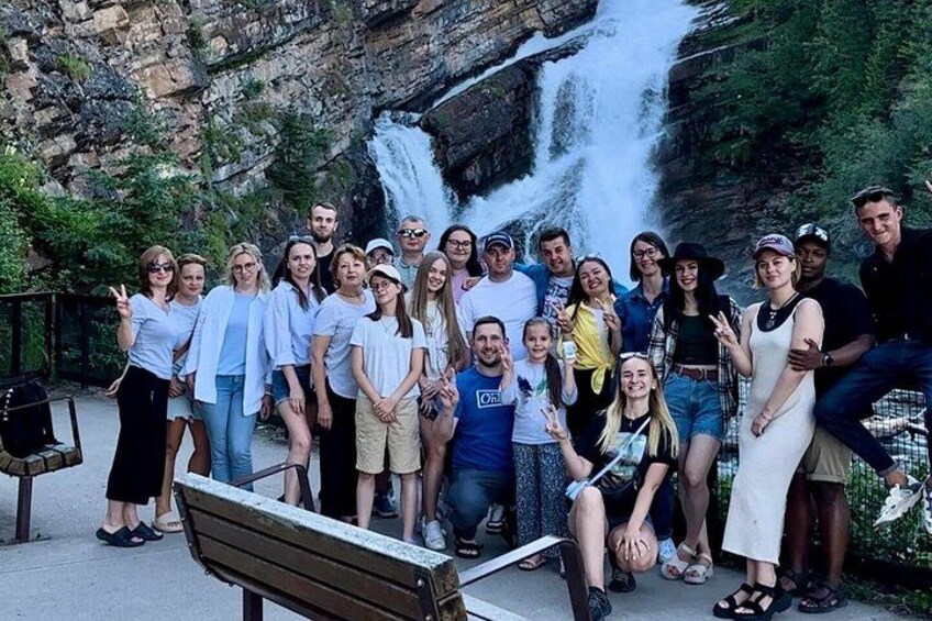 A group of people posing in front of a waterfall. 3
