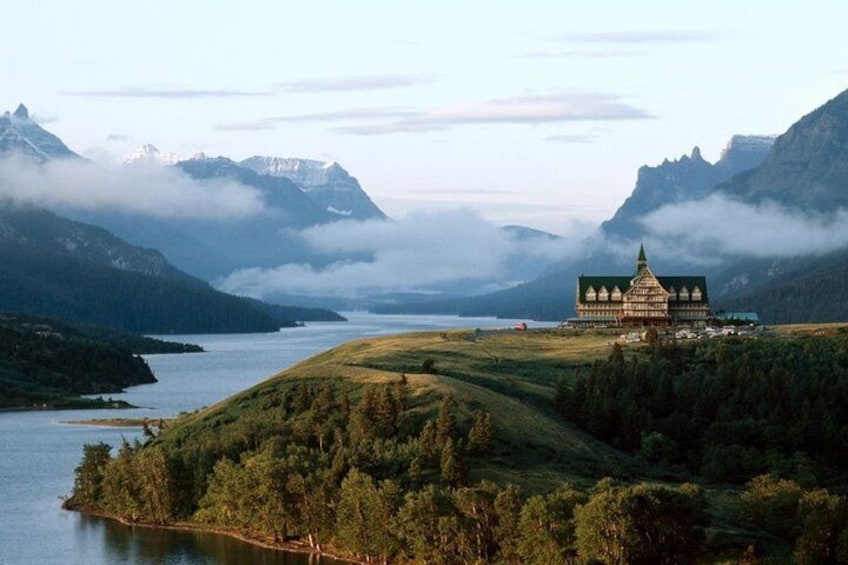 A mountain landscape with a lake, forested hills, and a building with a green roof. 2