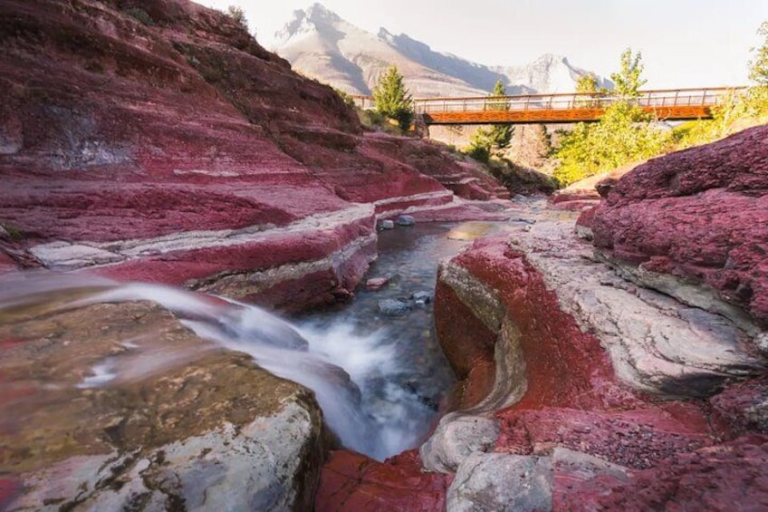 A river flowing through a canyon with red rock formations and a bridge in the background. 3