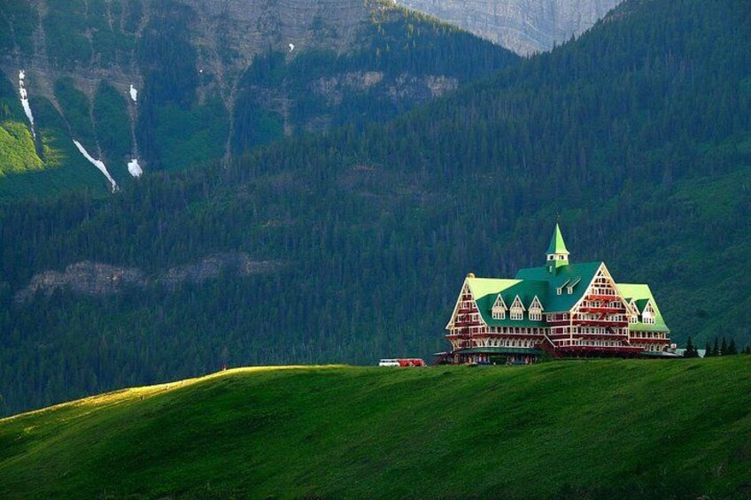 A large, traditional chalet with a green roof, set against a mountainous backdrop. 5
