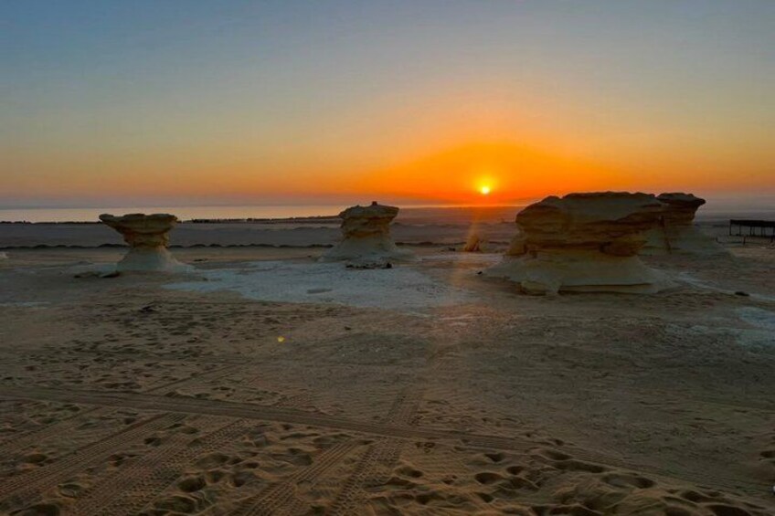 A sunset over a beach with rock formations. 1