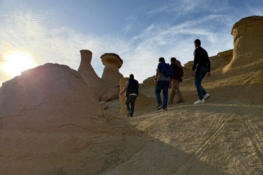 A group of people hiking on a desert trail with unique rock formations. 3