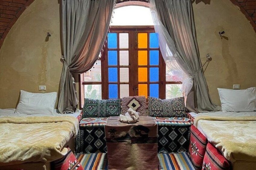A cozy room with two beds, colorful pillows, and a large window with curtains. 5