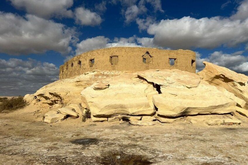 A historical stone structure with a flat roof, surrounded by large boulders. 4