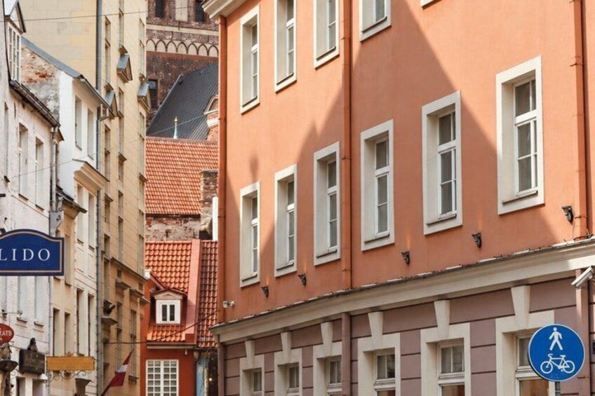 A street with buildings, a blue sign with a bicycle symbol, and a flag. 5