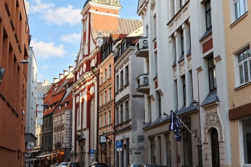 A street with historic buildings, a clock tower, and a parked car. 2