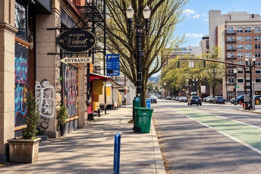 A street with a green bike lane, a parking sign, and a building with a sign reading 'Mother's Velvet Lounge of Cafe.' 2