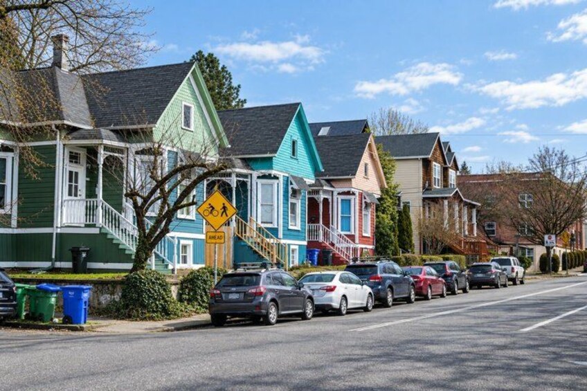 A street lined with colorful houses, parked cars, and a pedestrian crossing sign. 1
