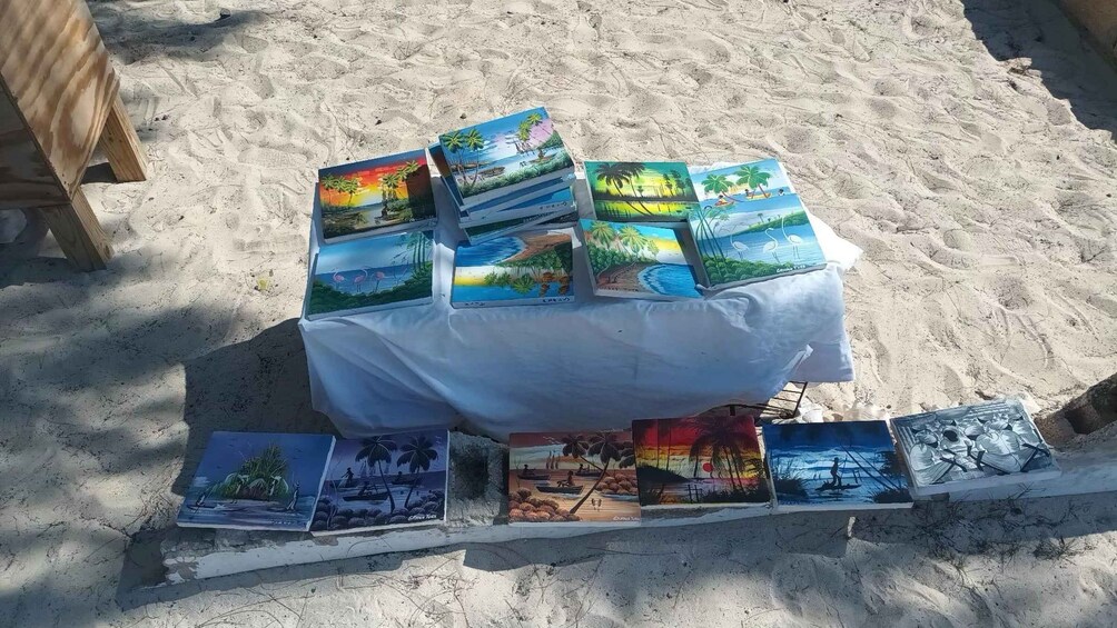 Une table surmontée de diverses peintures colorées, le tout installé sur une plage de sable. 5