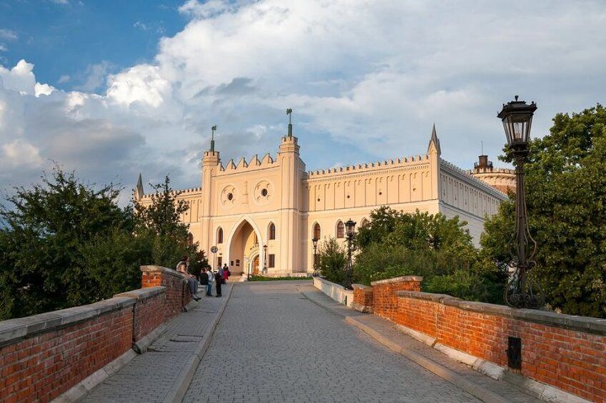 A historic building with arched windows and towers, a paved pathway, and a brick wall. 2
