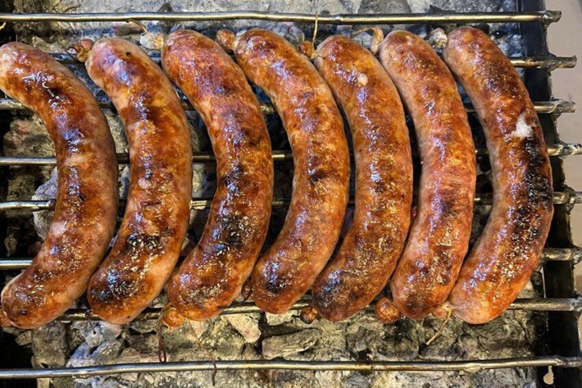 A row of sausages being grilled over an open flame. 3