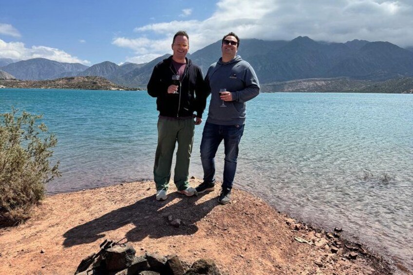Two people standing by a lake with mountains in the background. 5