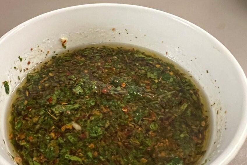 A bowl of green sauce with visible herbs and spices. 4