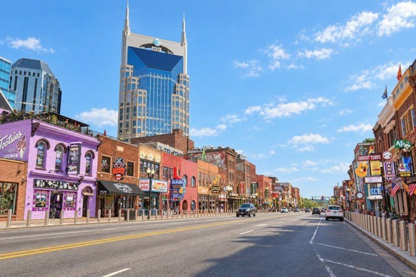 A city street lined with colorful buildings, a modern skyscraper, and a clear blue sky. 5