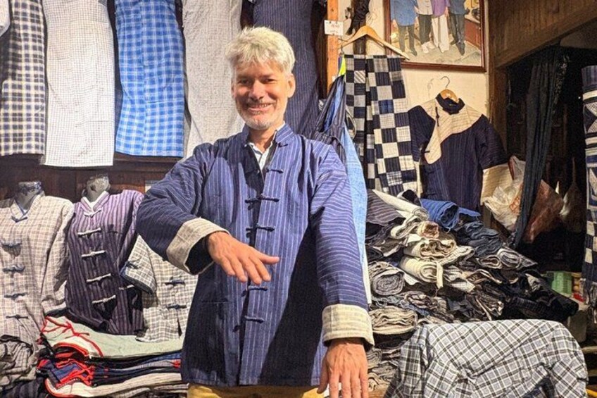 A person standing in a clothing store with various garments on display. 5