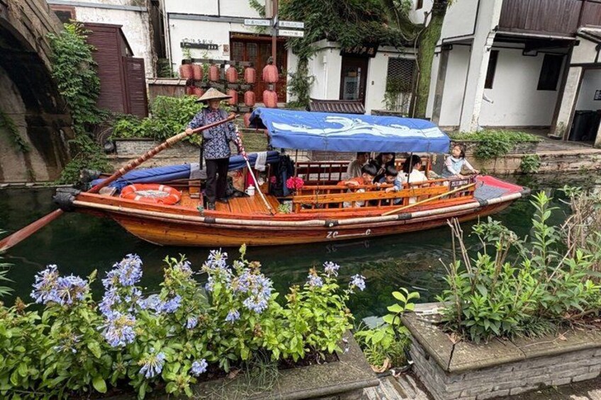 A traditional boat with passengers, a blue canopy, and a stone structure with plants. 1