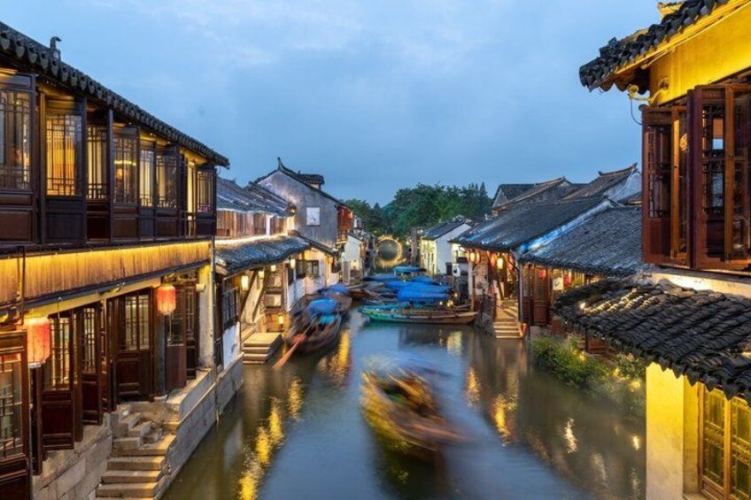 A traditional canal with wooden buildings on either side, boats, and a clear sky. 3
