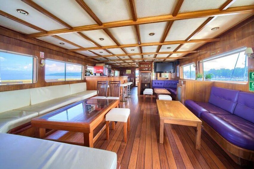 A boat's interior with wooden flooring, tables, and seating areas. 4