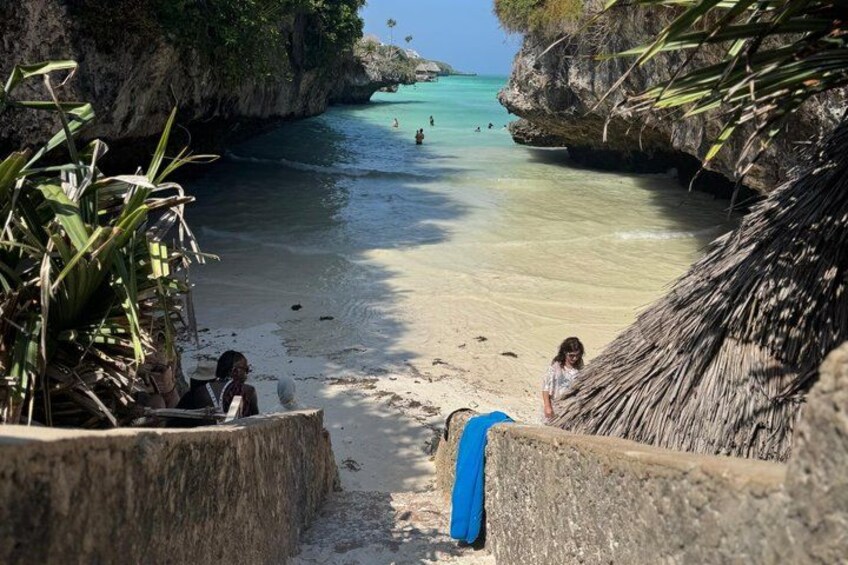 A beach with clear turquoise water, a thatched-roof structure, and a concrete staircase leading down to the shore. 2