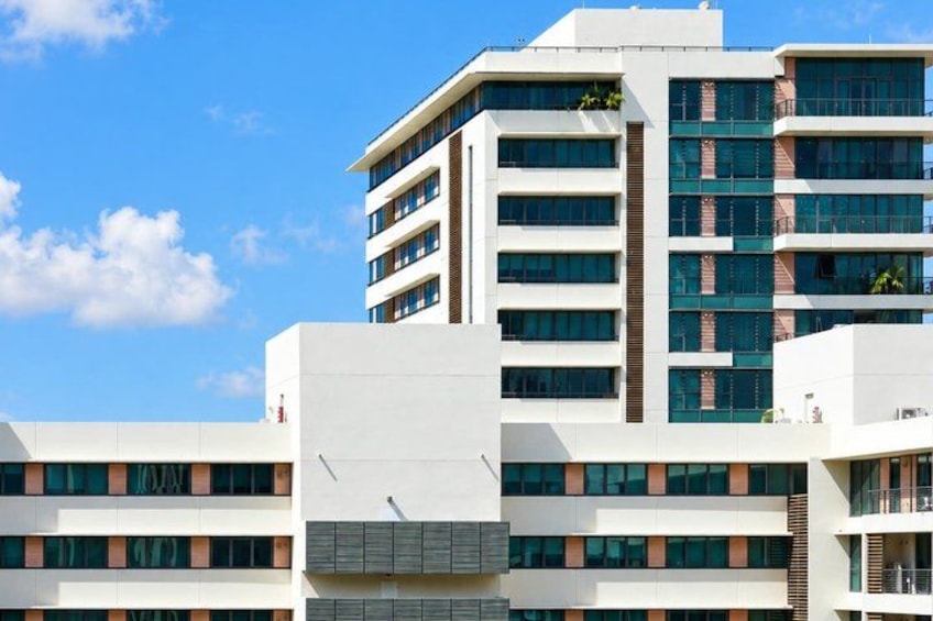 A modern multi-story building with a flat roof, large windows, and a white facade. 2