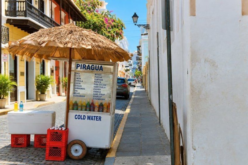 A street vendor cart with a sign listing cold drinks and a small cooler. 4